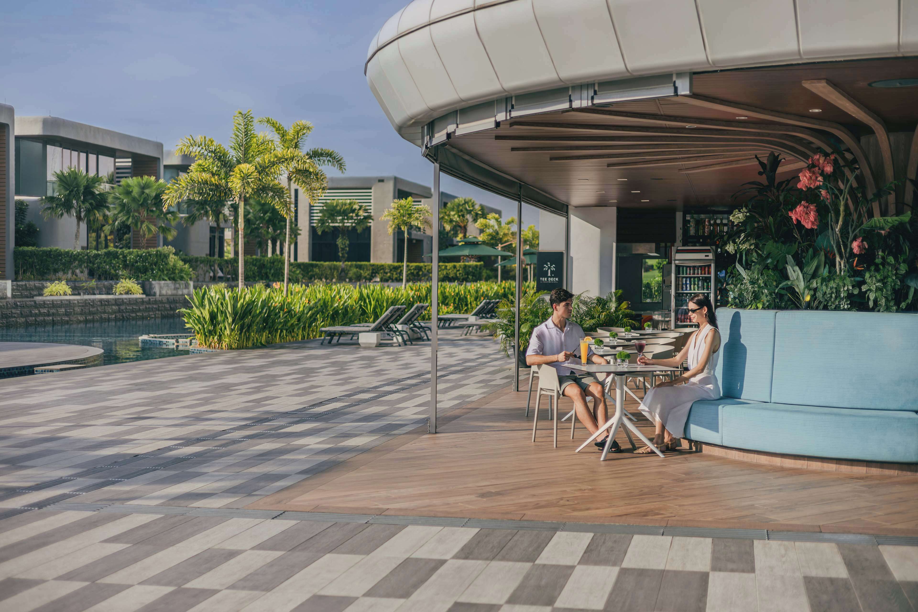 An outdoor seating area with a checkered floor, a blue sofa, and a table with two people.
