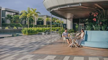 An outdoor seating area with a checkered floor, a blue sofa, and a table with two people.