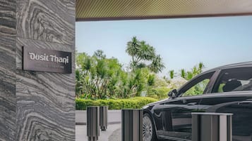 A black car parked in front of a building with a sign reading "Dusit Thani Lacuna - Singapore".
