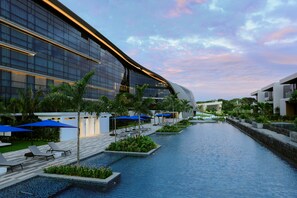 A modern hotel with a swimming pool, lounge chairs, and blue umbrellas. - Dusit Thani Laguna Singapore (Singapore)