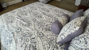 Un dormitorio con una cama grande, una mesita de noche, un espejo y una ventana con persianas.