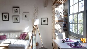 A modern living room with a white sofa, a coffee table, a tripod floor lamp, and a stone wall. - Live in the Shadow of the Acropolis (Athens)