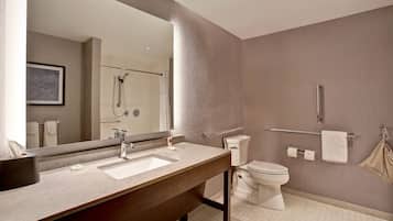 Un baño moderno con un espejo grande, dos lavamanos, inodoro y ducha.