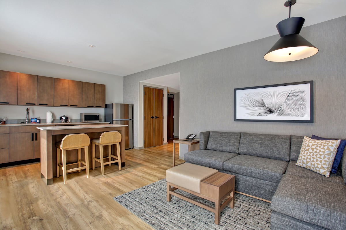 A modern living space with a kitchen, a sofa, and a dining area.
