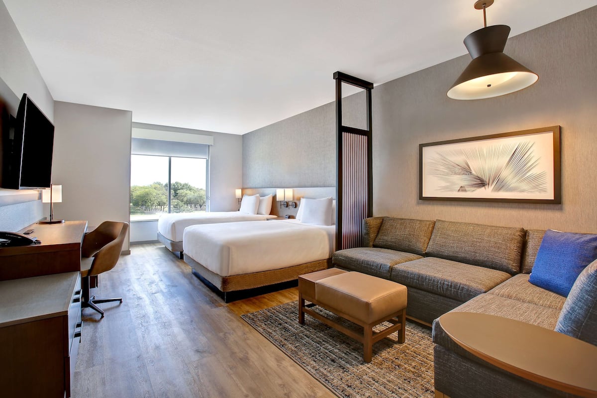 A modern hotel room with a large bed, a sofa, a desk, and a TV.