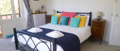 A neatly made bed with colorful pillows, a bedside table with a lamp, and a wall with pictures.