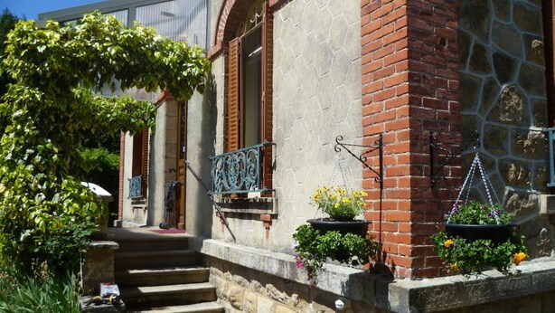 Un bâtiment doté d’une façade en pierre, d’une partie en briques et d’un garde-corps de balcon en métal.