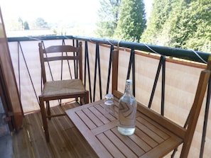 A wooden deck with a table and a chair, a bottle, and a glass.