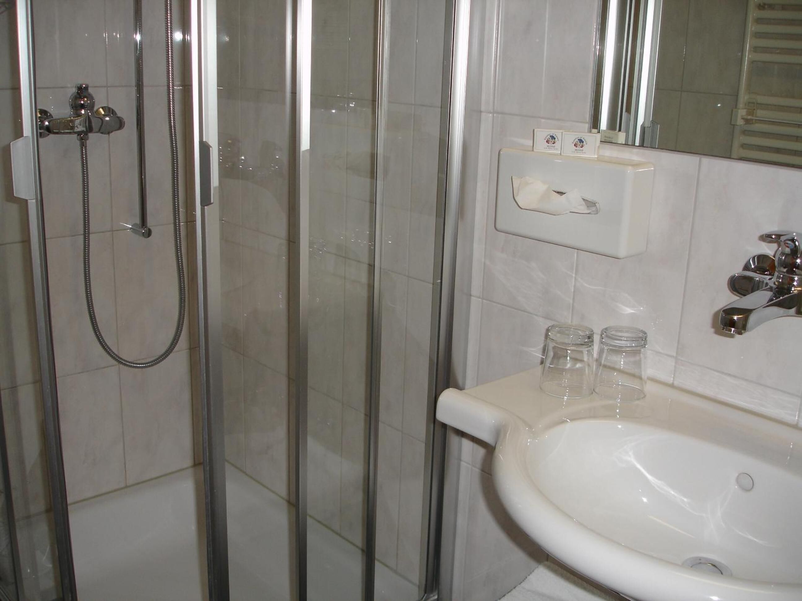 A bathroom with a glass-enclosed shower, a white sink, and a mirror above the sink.