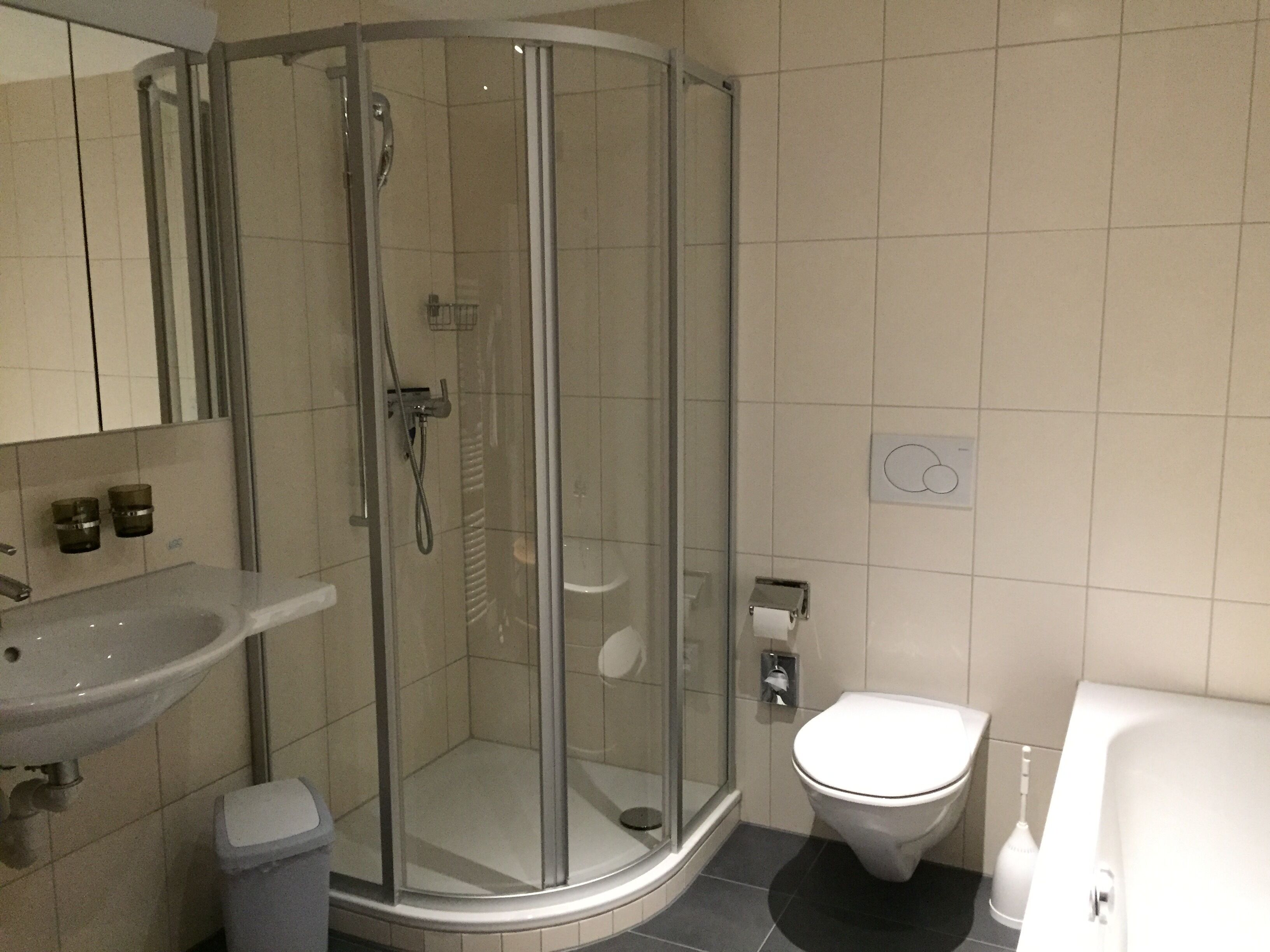 Un baño moderno con ducha de vidrio, lavamanos y un inodoro.