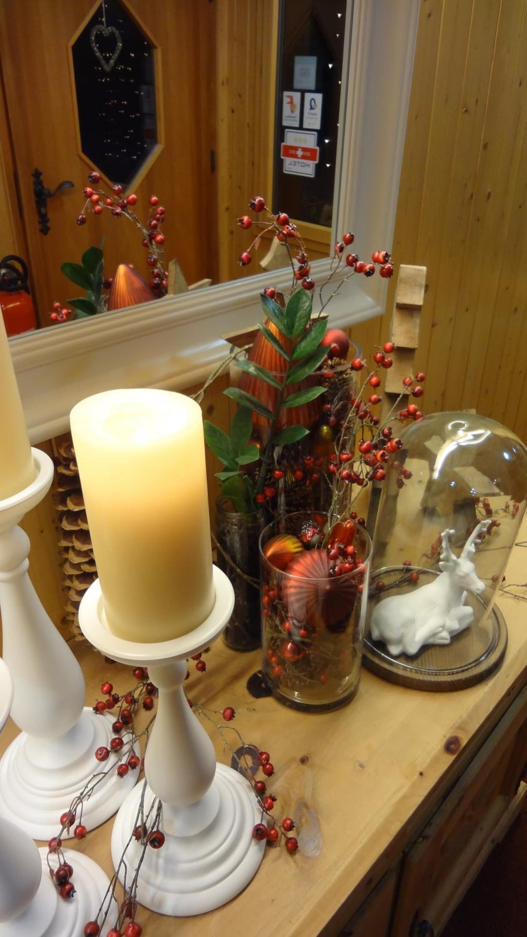 Un comptoir en bois orné d’une grande bougie, de beaux objets en verre décoratifs et d’un miroir qui reflète la pièce.