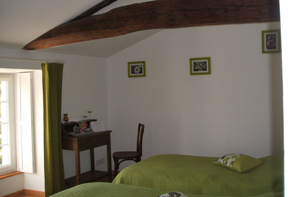 A room with a bed, a chair, a desk, and a window with curtains.