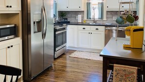 Una cocina moderna con armarios blancos, electrodomésticos de acero inoxidable y piso de madera.