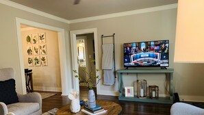 Una sala de estar con televisor, una mesa de centro con libros y un jarrón, y un sofá.