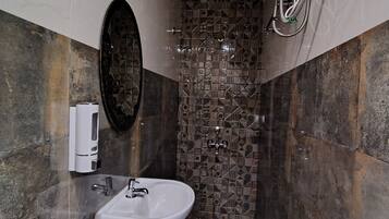 A bathroom with a sink, a mirror, a shower, and a toilet.