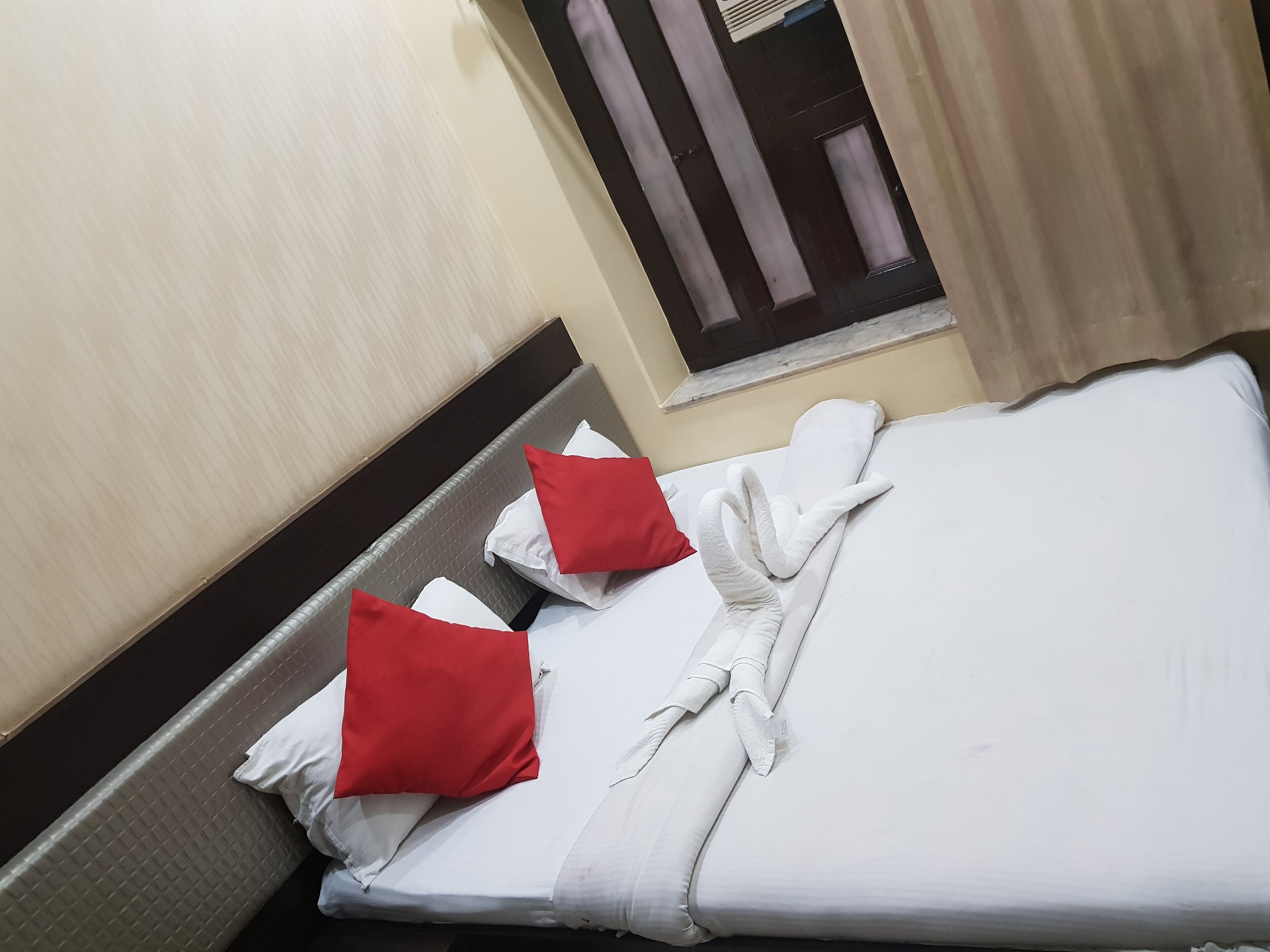 Une chambre d’hôtel avec un lit, des oreillers et une fenêtre avec des rideaux.