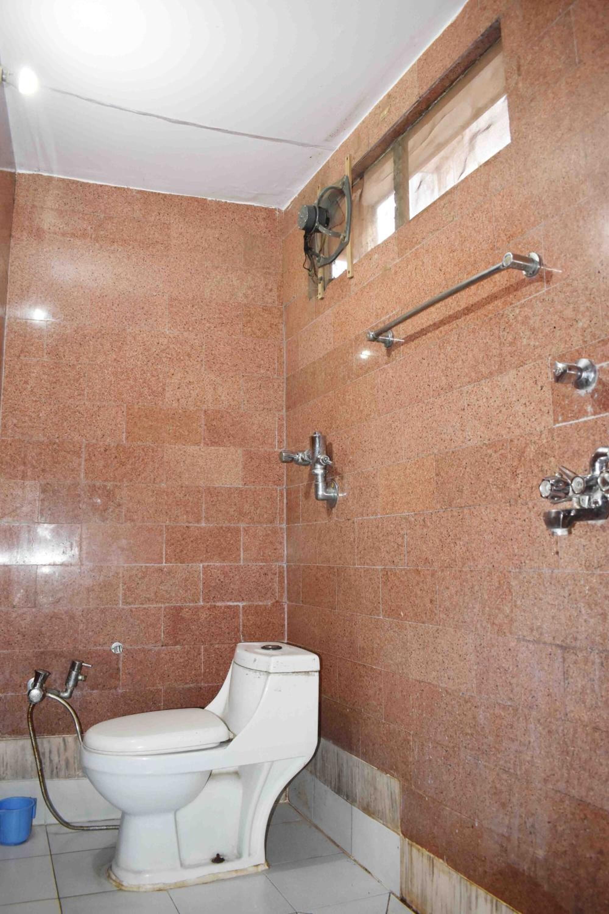 Un baño con inodoro blanco, ducha y barras de apoyo.