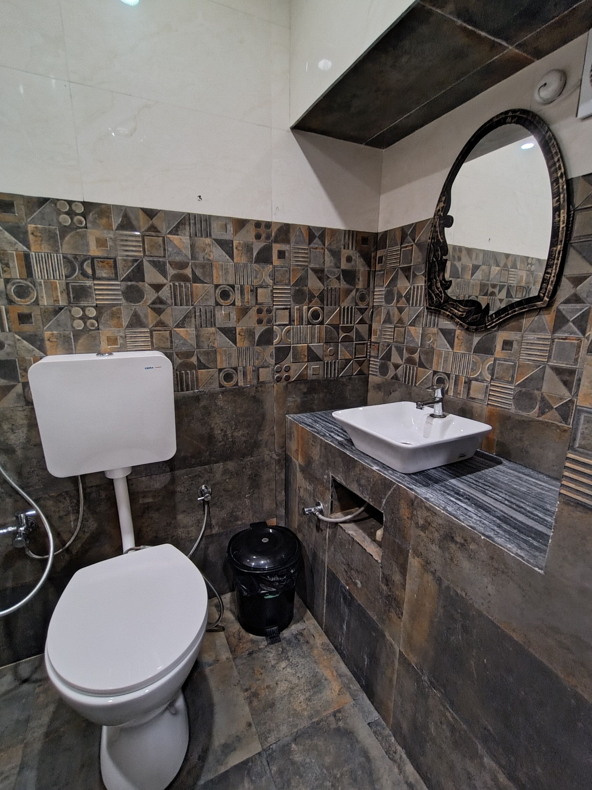A bathroom with a toilet, sink, and a black trash bin.
