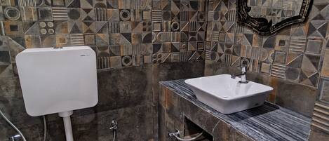 A bathroom with a toilet, sink, and a black trash bin.