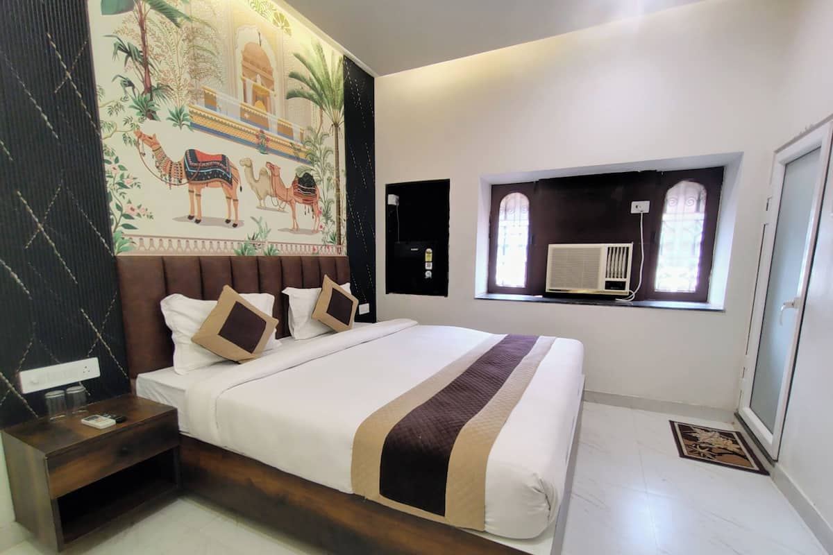 Une chambre à coucher avec un grand lit, une table de chevet, une fresque murale, une fenêtre avec un climatiseur et une porte.