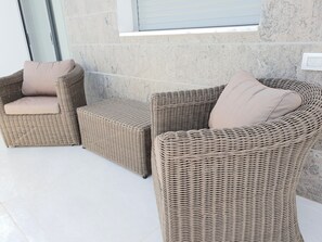 Un conjunto de sofá de mimbre con cojines, ubicado cerca de una ventana con vistas al exterior.