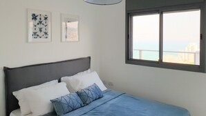 Een slaapkamer met een bed, een raam met uitzicht en twee ingelijste foto's aan de muur.