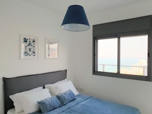 Un dormitorio con cama, ventana con vistas y dos cuadros en la pared.