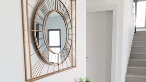 Een modern interieur met een donkergrijze console tafel, een spiegel met gouden lijst en twee kleine potplanten.