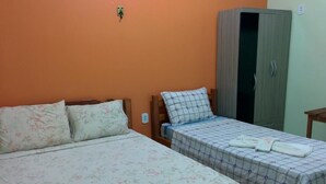 A room with two beds, one with floral bedding and the other with checkered bedding, a wardrobe, and a small table. - Hotel e restaurante Toraryca (Belém)