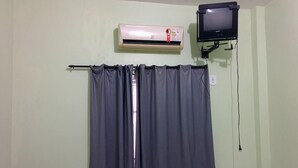 A room with a grey curtain, an air conditioner, and a television mounted on the wall. - Hotel e restaurante Toraryca (Belém)