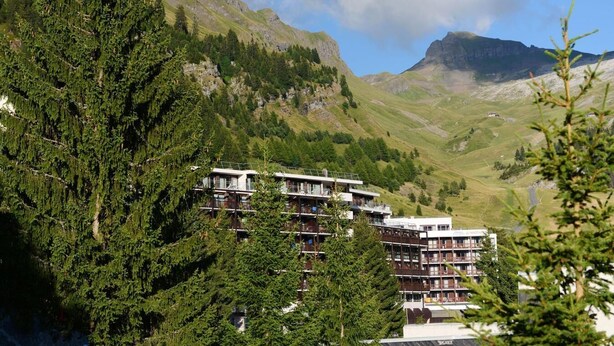 A multi-story hotel with balconies, surrounded by dense forest and mountains. - Wifi, 100m from resort center, swimming pool, balcony, tv, ski locker, 58m², Flaine (Flaine)