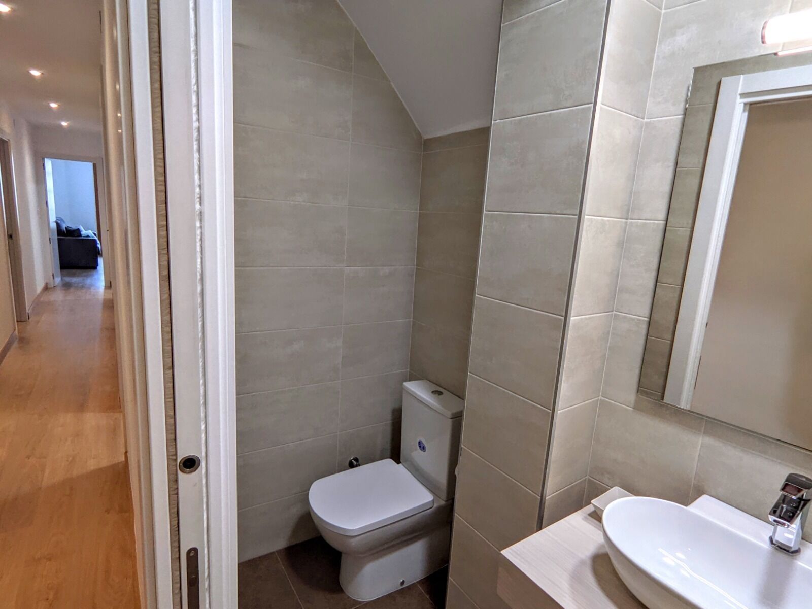 A modern bathroom with a toilet, sink, and mirror.