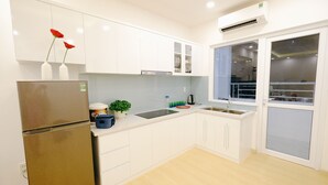 Eine moderne Küche mit weißen Schränken, einem Edelstahlkühlschrank, einer Spüle und einem Fenster mit Blick.