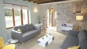 A living room with a grey sofa, a white coffee table with plants, a yellow armchair, and a stone wall with a wooden ceiling. - Beautiful house to share with friends or family (Nanteuil-sur-Marne)