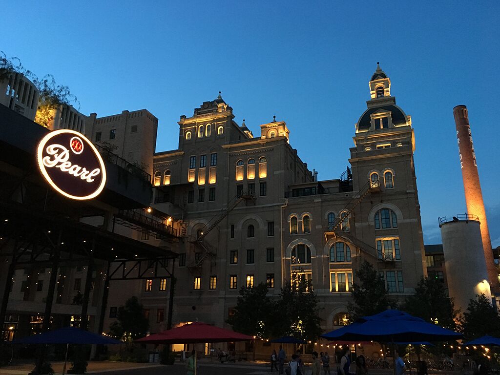 Un edificio histórico con ventanas de arco y una torre destacada, iluminado con una cálida luz.