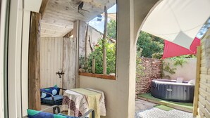 A small patio area with a table and two chairs, a hot tub, and a stone wall. - Mas Maurane Chambre d'hôtes (Tarascon)
