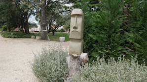 A stone monolith in a park with surrounding greenery and a gravel path. - Mas Maurane Chambre d'hôtes (Tarascon)
