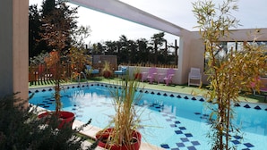 A swimming pool with a checkered pattern, surrounded by potted plants and outdoor furniture. - Mas Maurane Chambre d'hôtes (Tarascon)