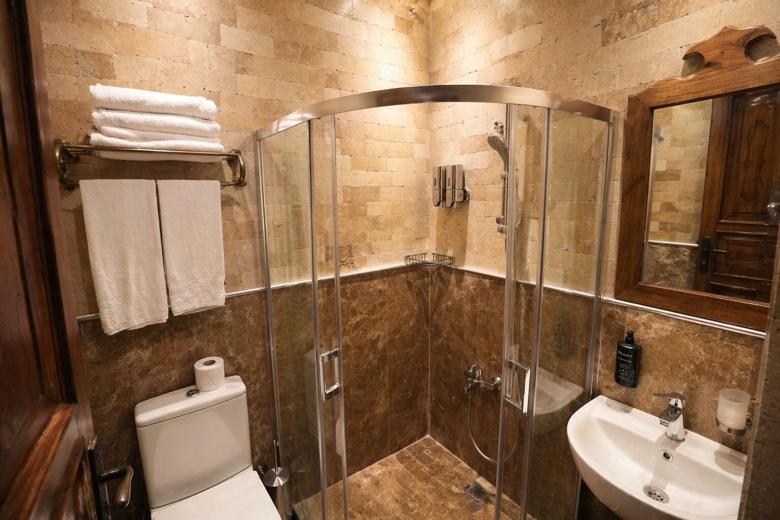 A bathroom with a glass-enclosed shower, a sink, a toilet, and a towel rack.