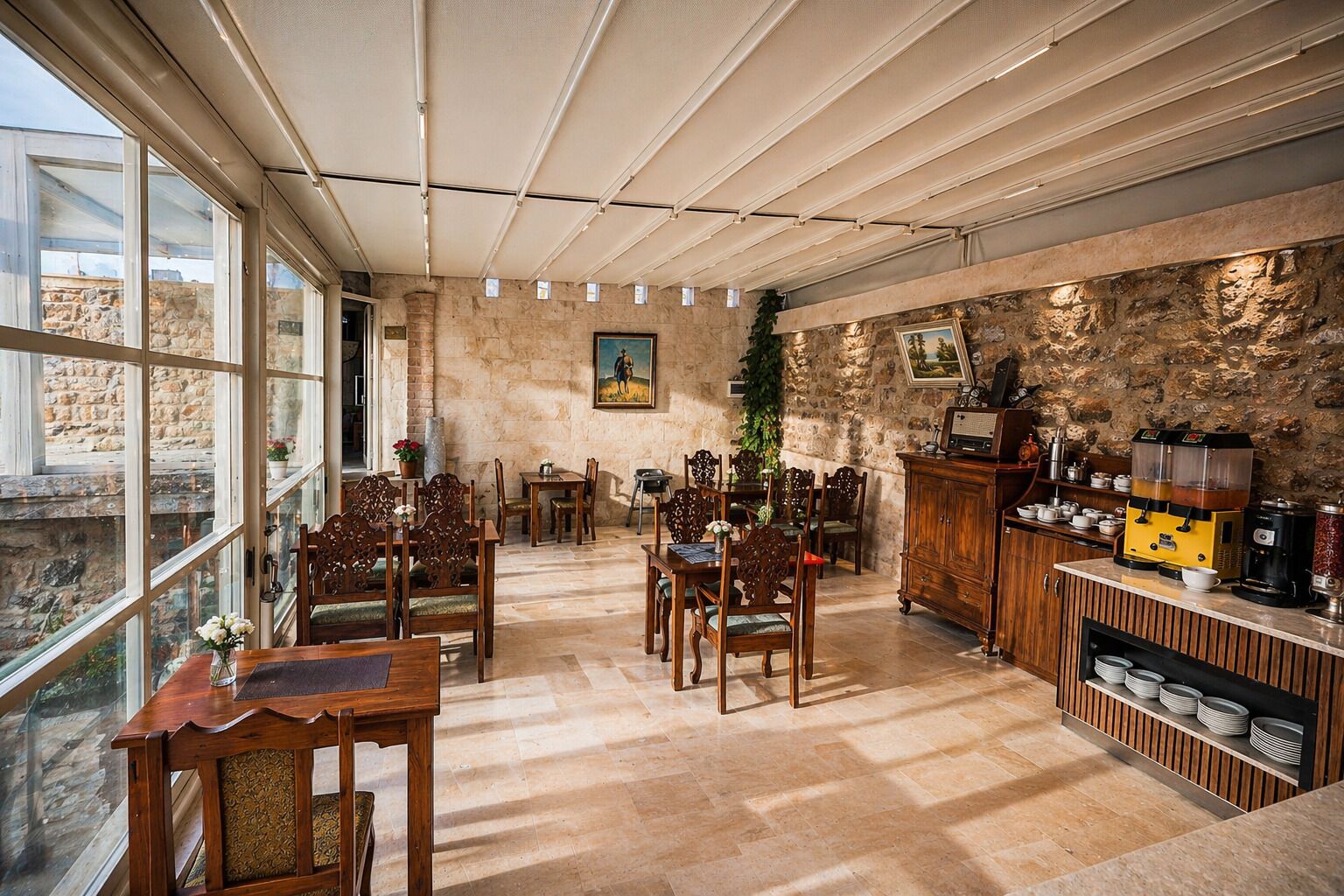 Une salle à manger spacieuse avec de hauts plafonds, des murs en pierre et une vue dégagée grâce à de grandes fenêtres.
