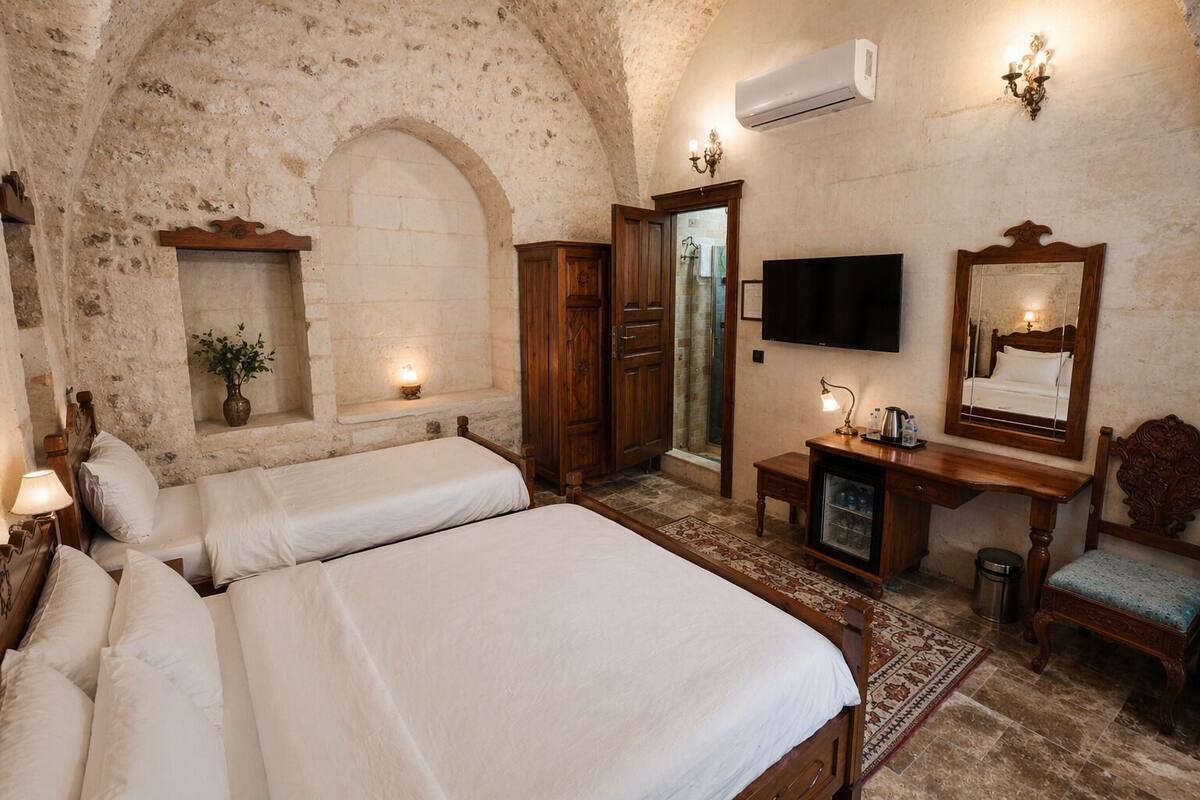 A room with two beds, a TV, a mirror, a desk, and a small cabinet.