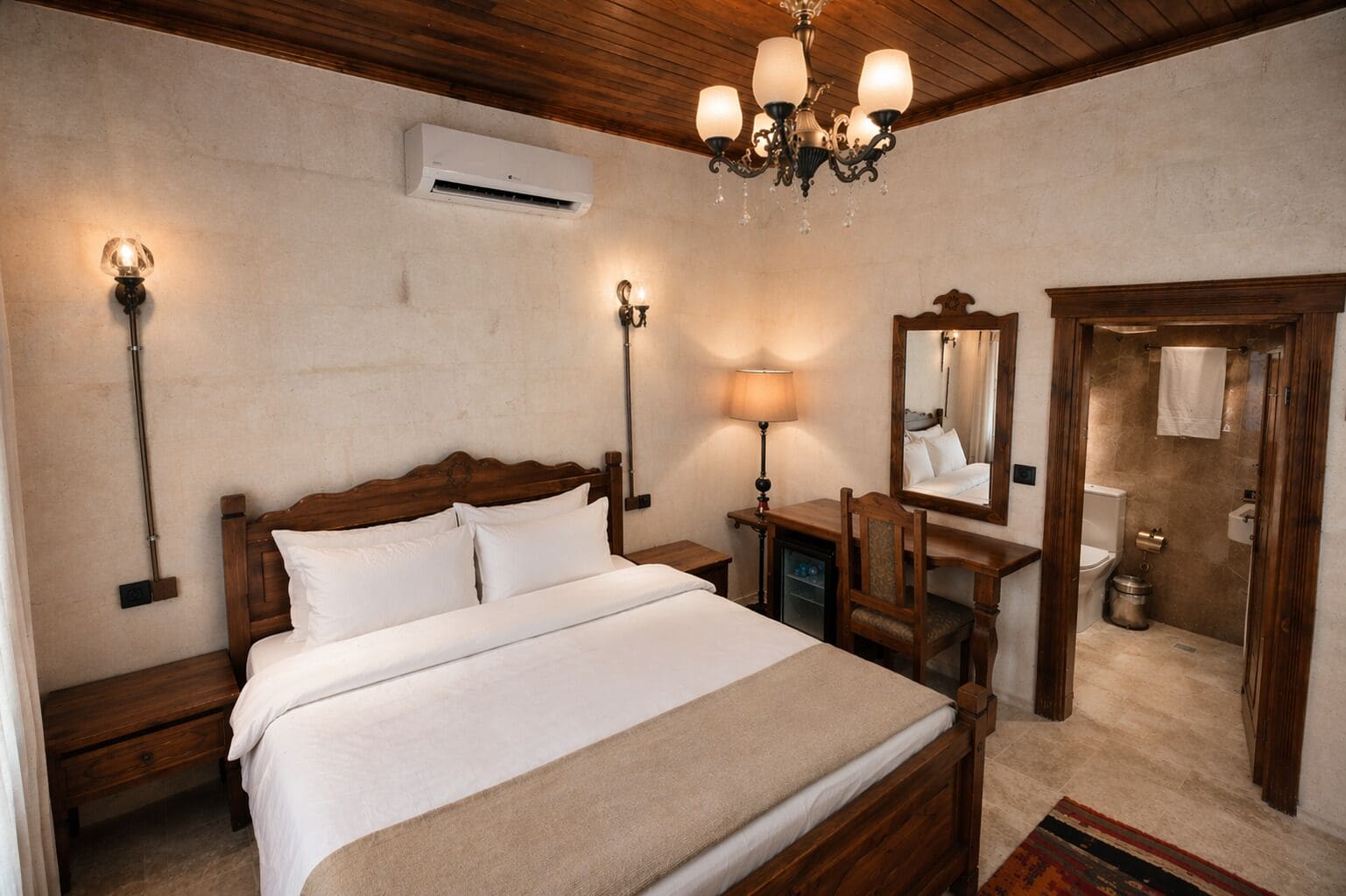 A bedroom with a wooden bed, bedside lamps, a desk with a mirror, and an air conditioning unit.