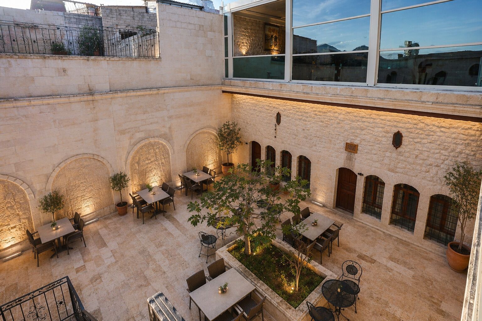 An outdoor courtyard with stone walls, arched doorways, and tables and chairs arranged for dining.