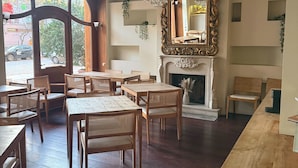 A dining area with wooden tables and chairs, a fireplace, and a large ornate mirror. - Numa Berlin Belfort (Berlin)
