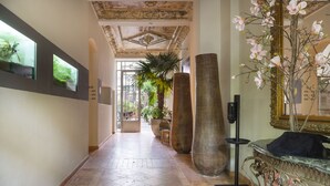 A spacious hallway with a tiled floor, large vases, and a decorative mirror. - Numa Berlin Belfort (Berlin)