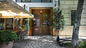 A cobblestone pathway leading to a wooden double door with a number plate, flanked by outdoor seating and potted plants. - Numa Berlin Belfort (Berlin)