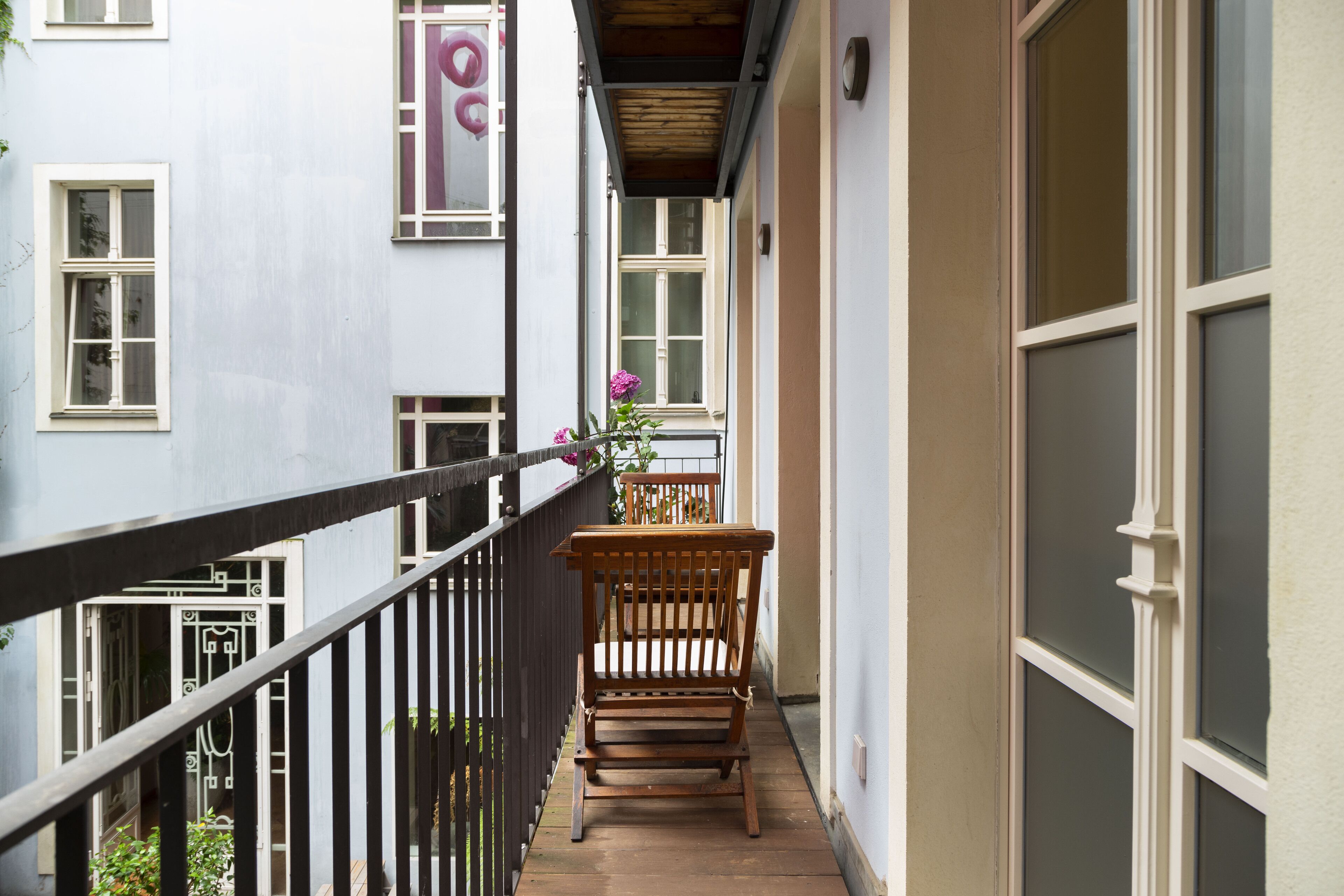 Ein schmaler Balkon mit einer hölzernen Bank und einem Blumentopf.