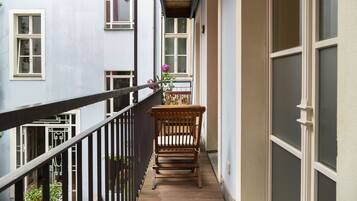 Ein schmaler Balkon mit einer hölzernen Bank und einem Blumentopf.