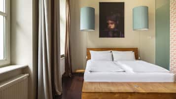 Un dormitorio con una cama plataforma de madera, dos lámparas fijadas a la pared, una ventana con cortinas y un cuadro enmarcado en la pared.