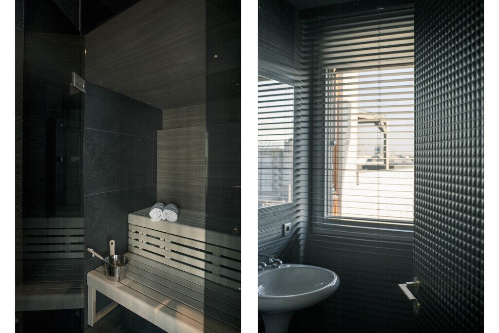 Un baño moderno con un banco, un lavabo y una ventana con persianas.